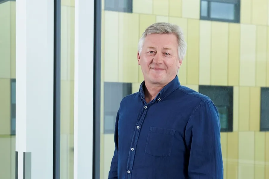 En mann som står foran en gul og grønn vegg