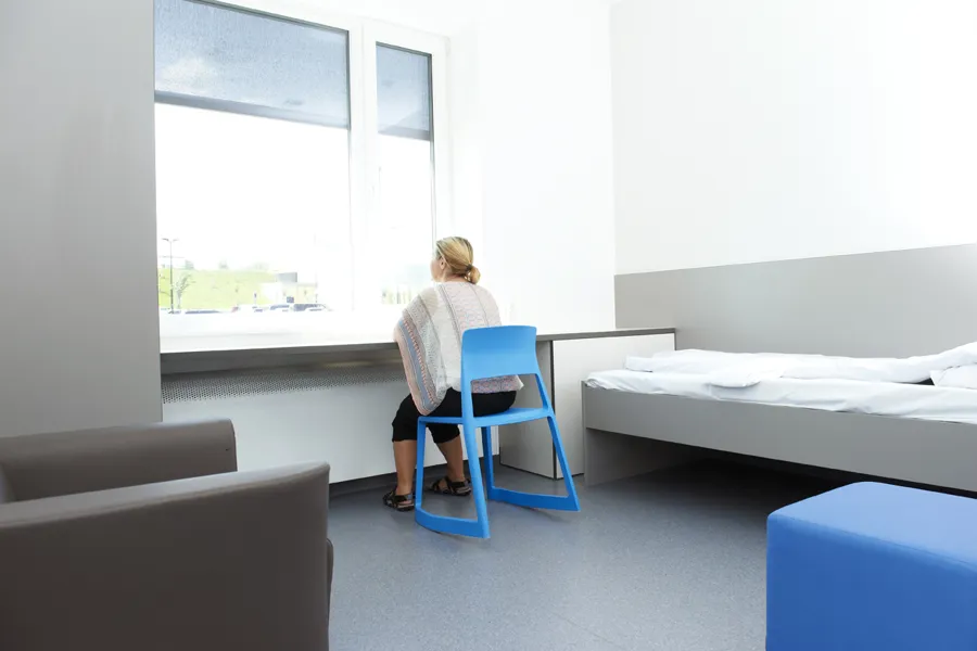 En person som sitter på en stol i et rom med vindu