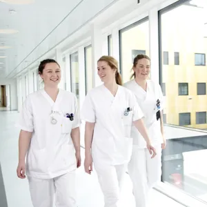 Tre sykepleiere går i en korridor