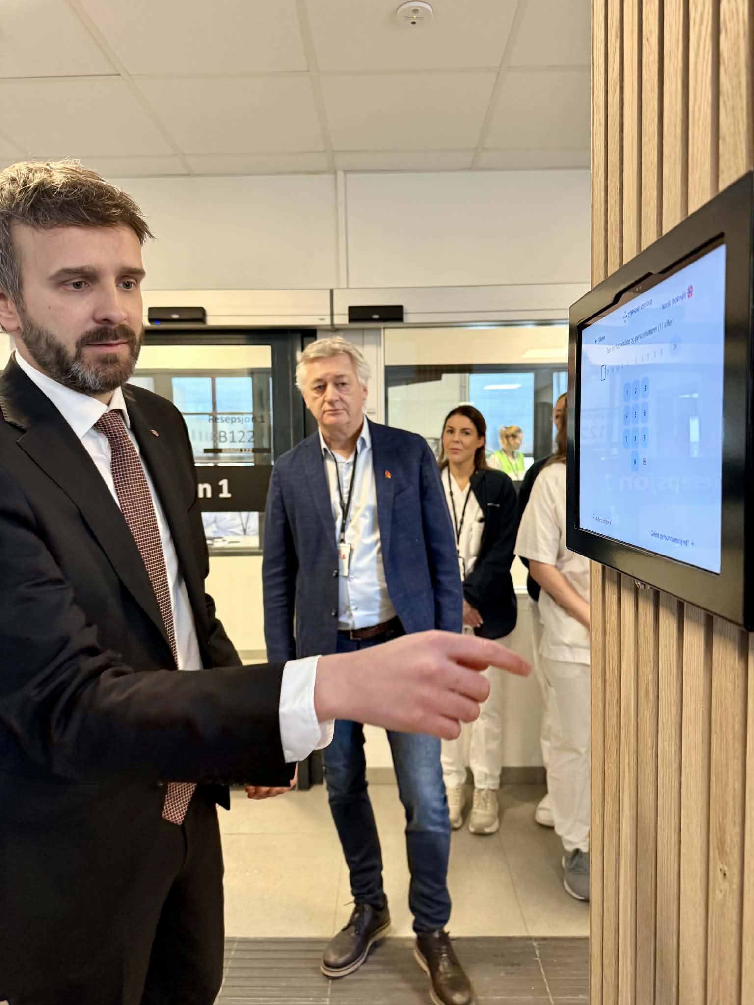 En mann i dress som peker på en skjerm