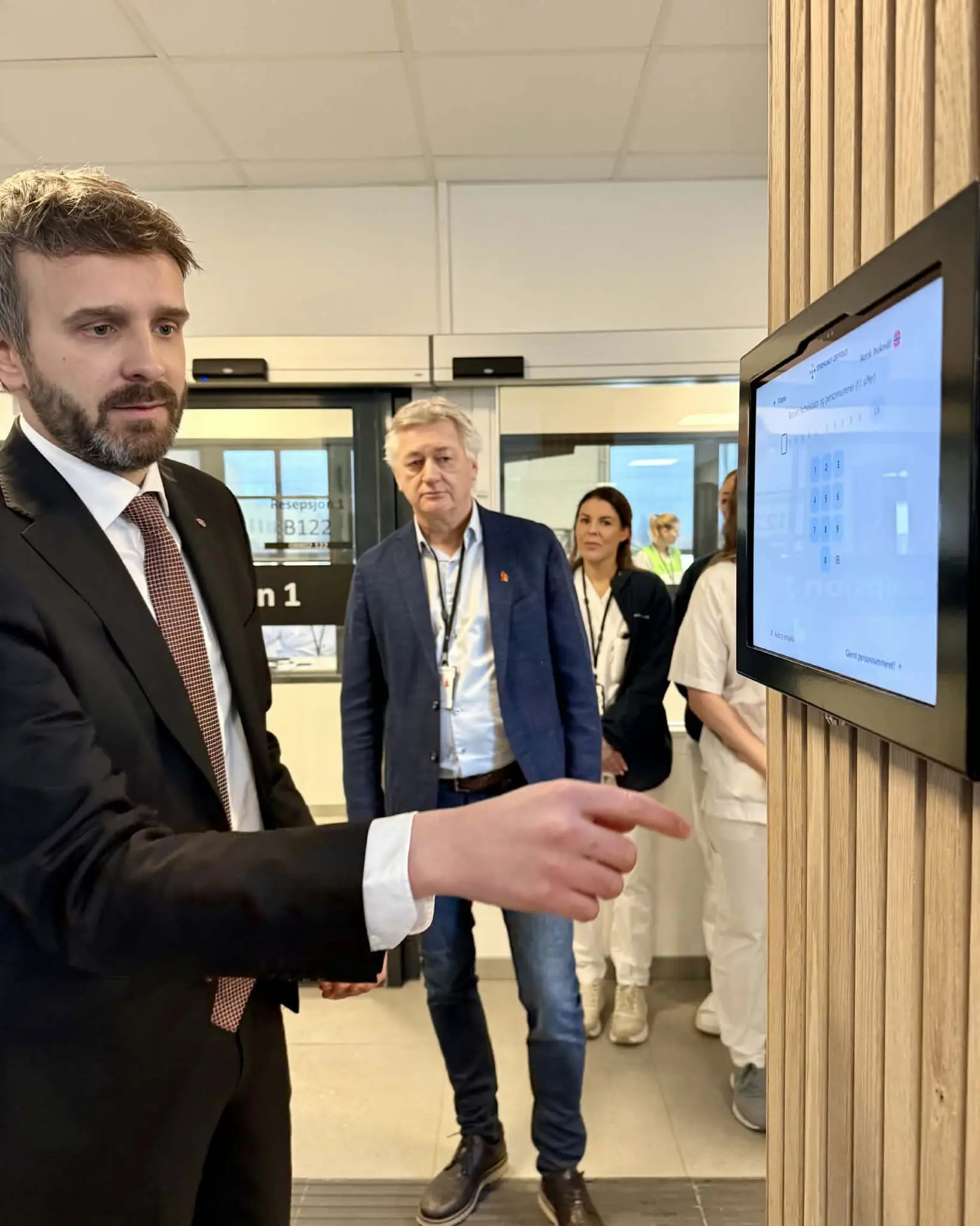 En mann i dress som peker på en skjerm