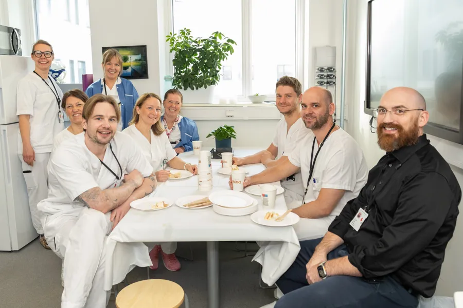 En gruppe mennesker som sitter rundt et bord med mat på