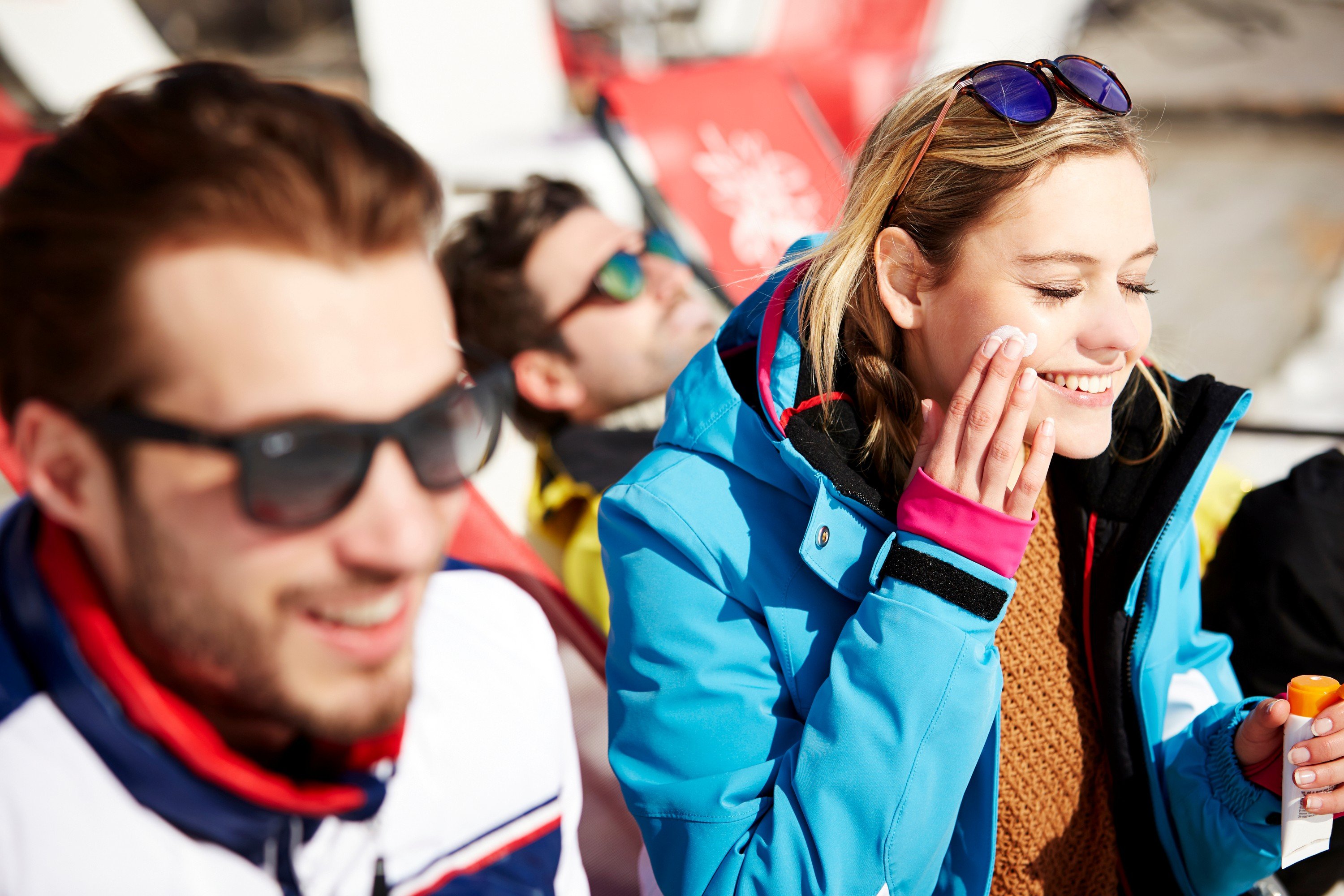 En mann og en kvinne som smiler og smører seg med solkrem