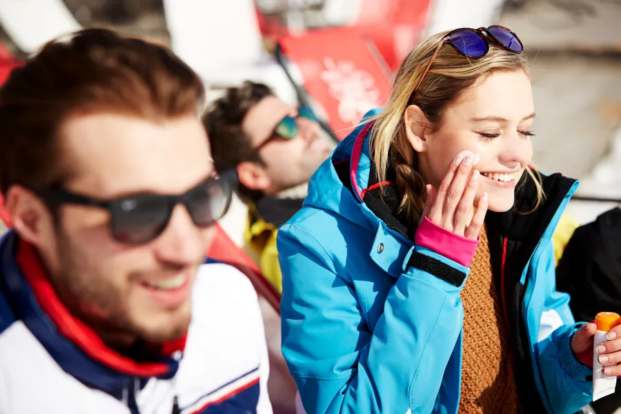 En mann og en kvinne som smiler og smører seg med solkrem