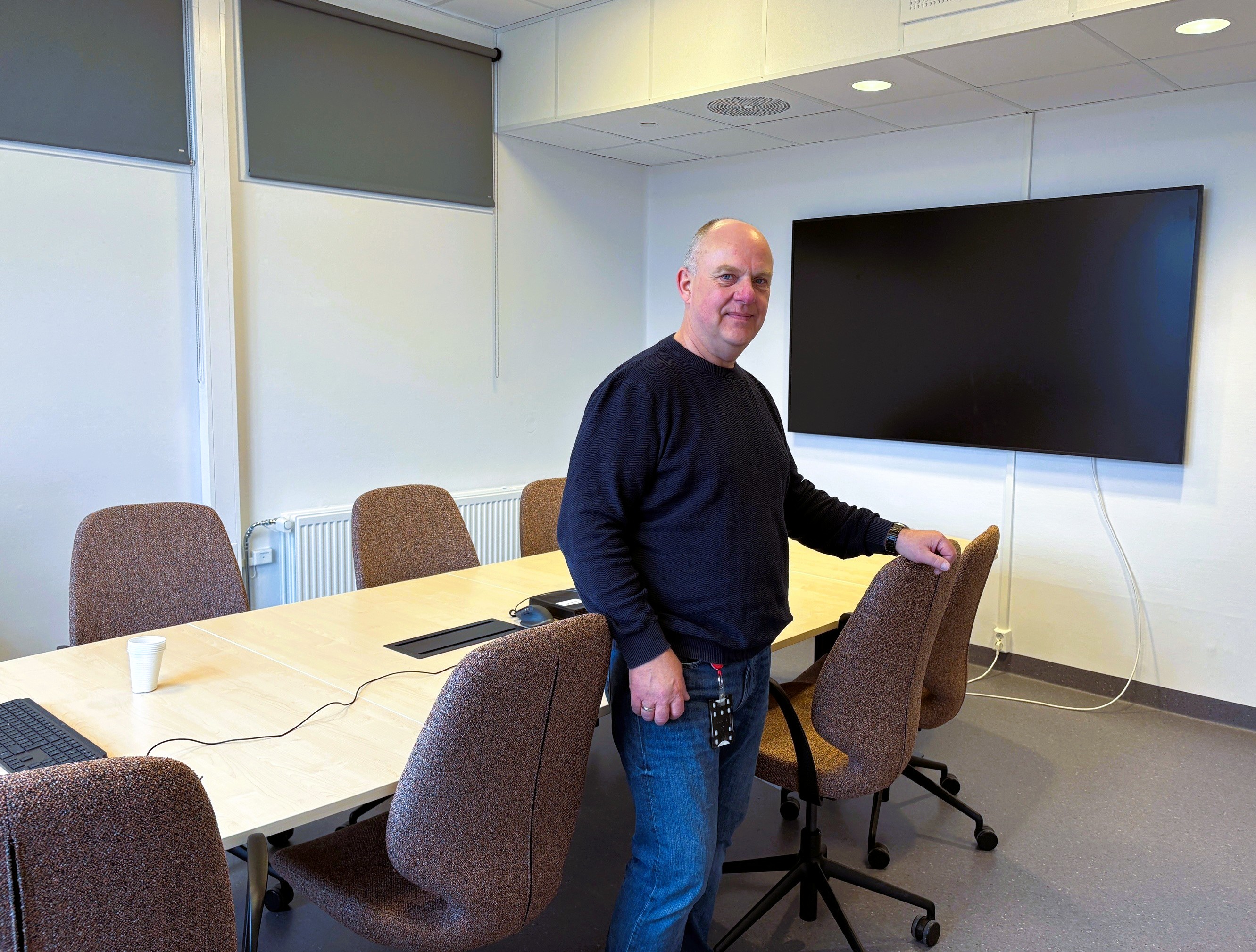 En person som står foran et bord med en skjerm bak seg