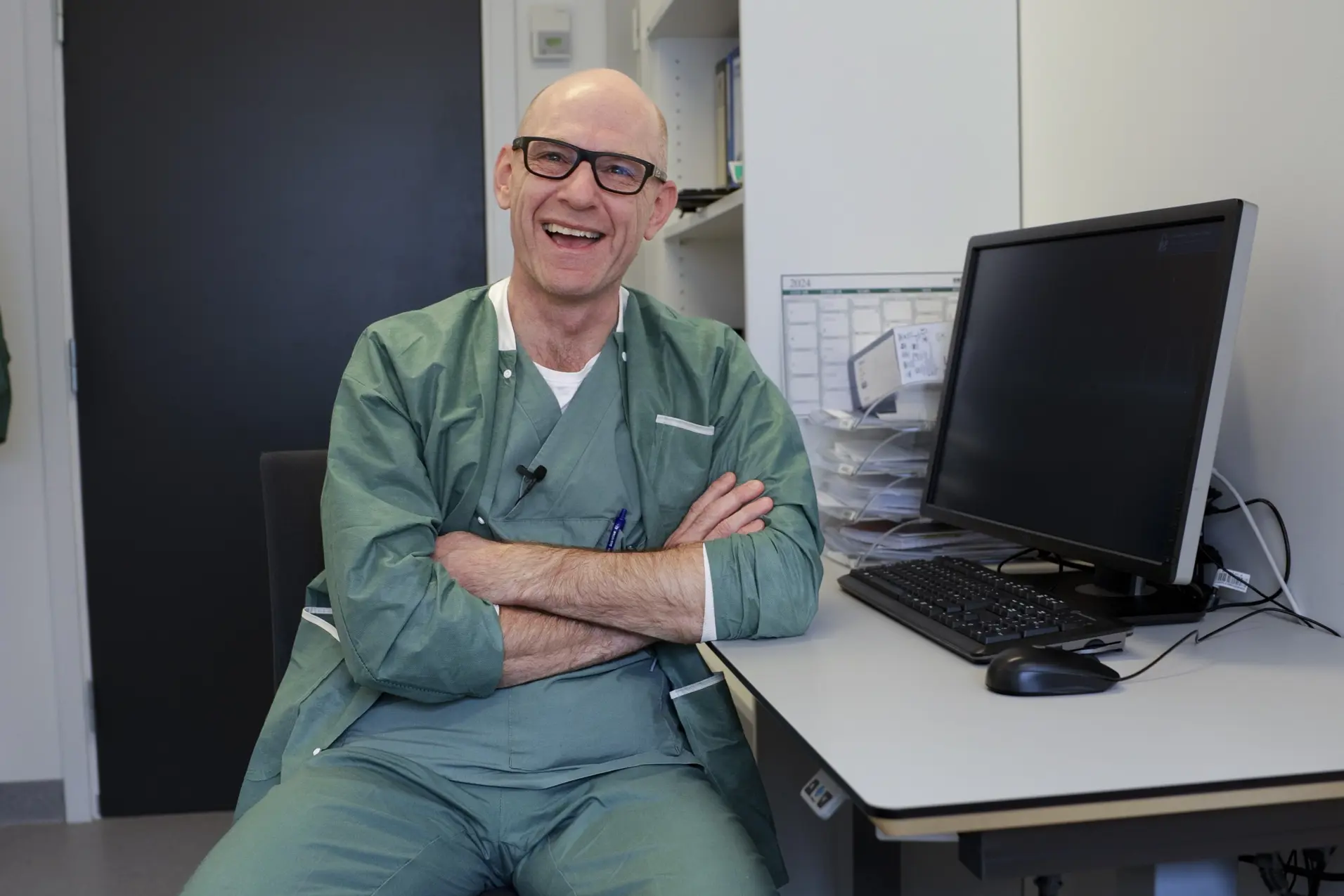 En person som sitter ved et skrivebord med armene krysset