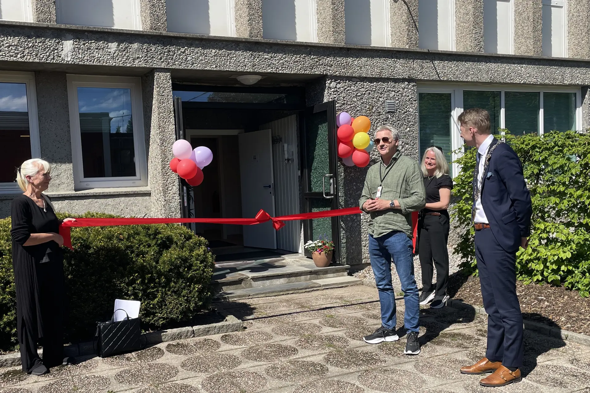 En gruppe mennesker som står utenfor et hus med ballonger