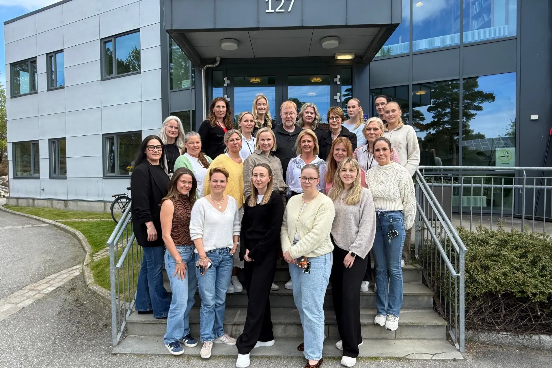 En gruppe mennesker som poserer for et bilde utenfor en bygning