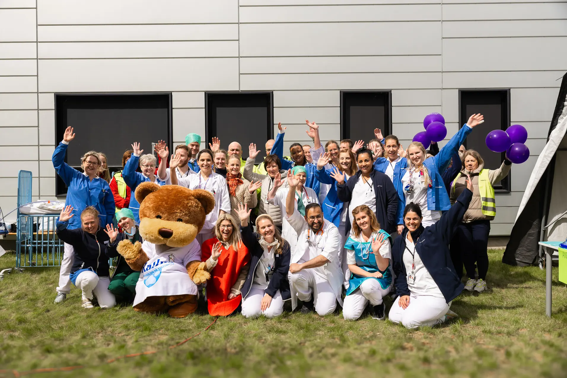 En gruppe mennesker som poserer med en bamse