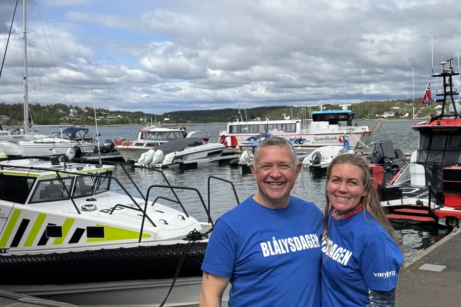 En mann og kvinne som poserer for et bilde ved siden av en marina full av båter