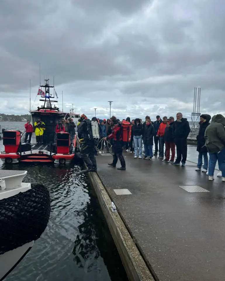 En gruppe mennesker som står på en brygge