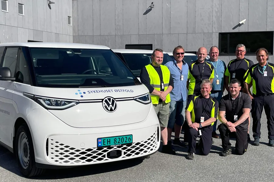 En gruppe mennesker som poserer for et bilde ved siden av en hvit bil