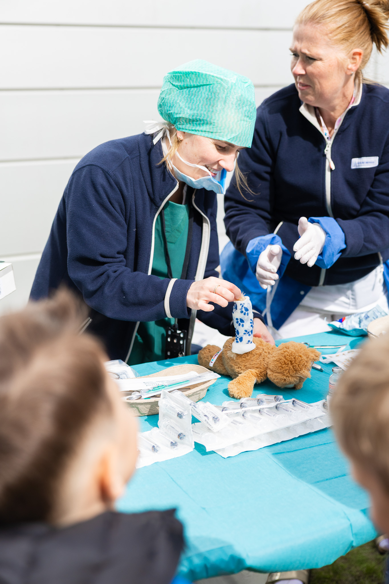 En person i arbeidsklær og maske som holder en teddybjørn