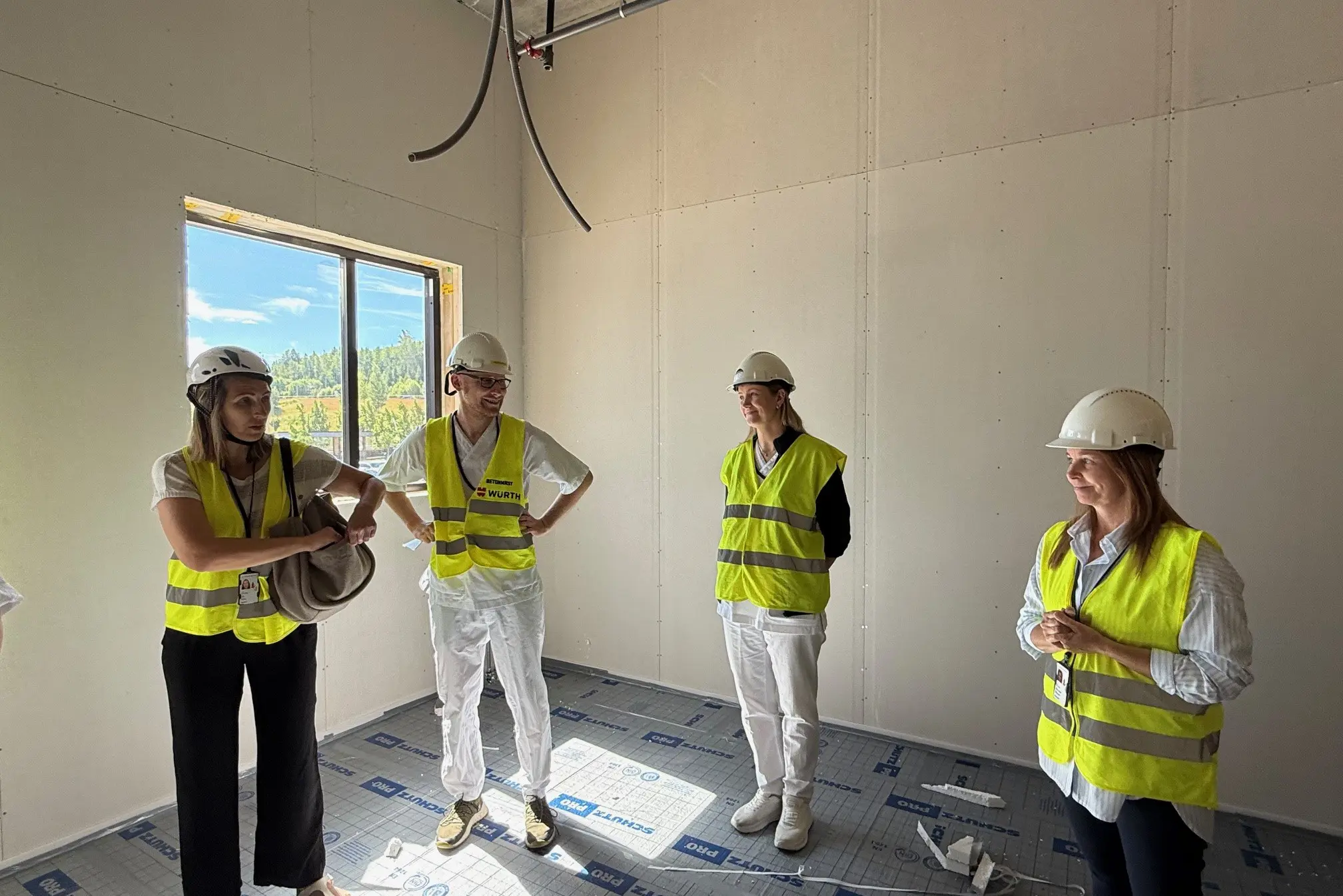 En gruppe arbeidere i sikkerhetsvester som står i et rom