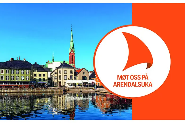 Et rødt og hvitt skilt med en bygning og et tårn i bakgrunnen