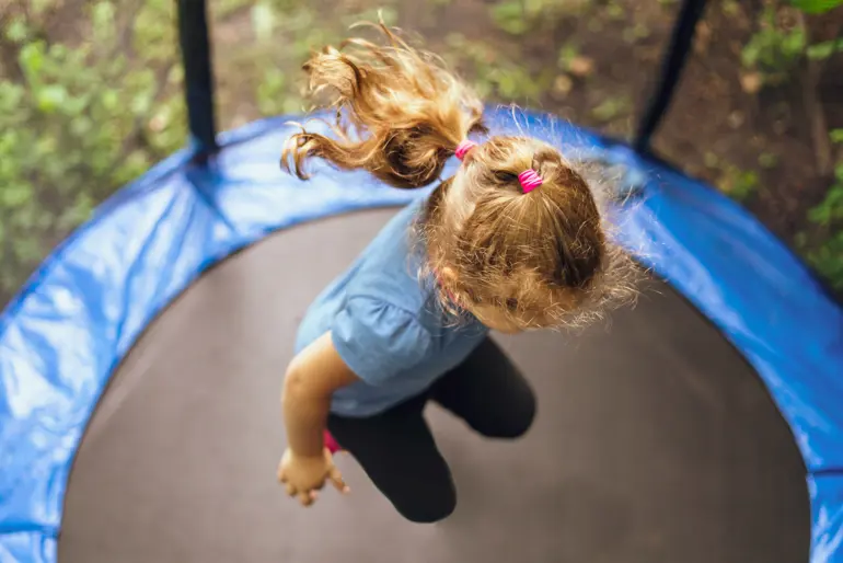En person som ligger på en trampoline med en hund på ryggen