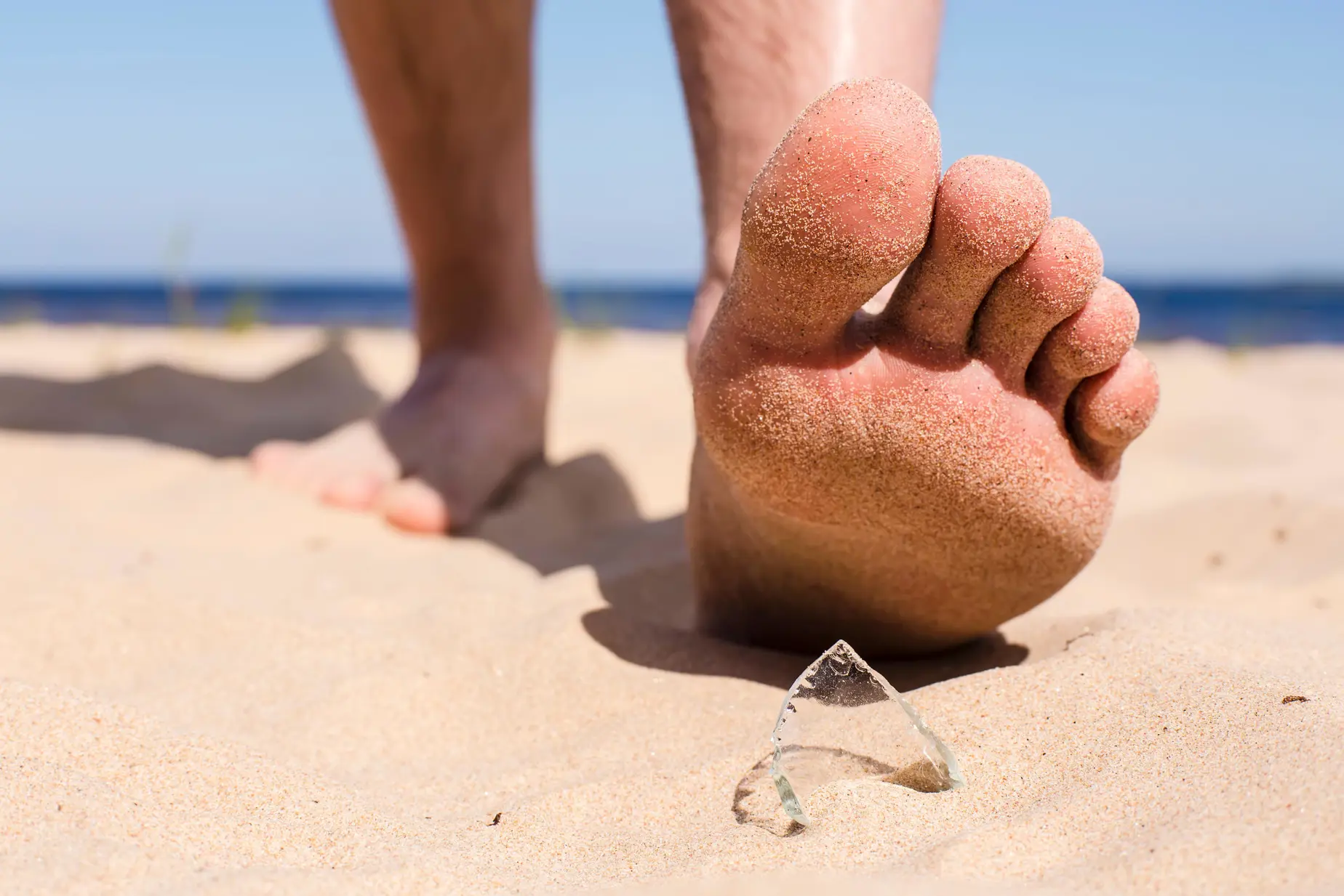 En persons fot på en strand med en ring på sanden