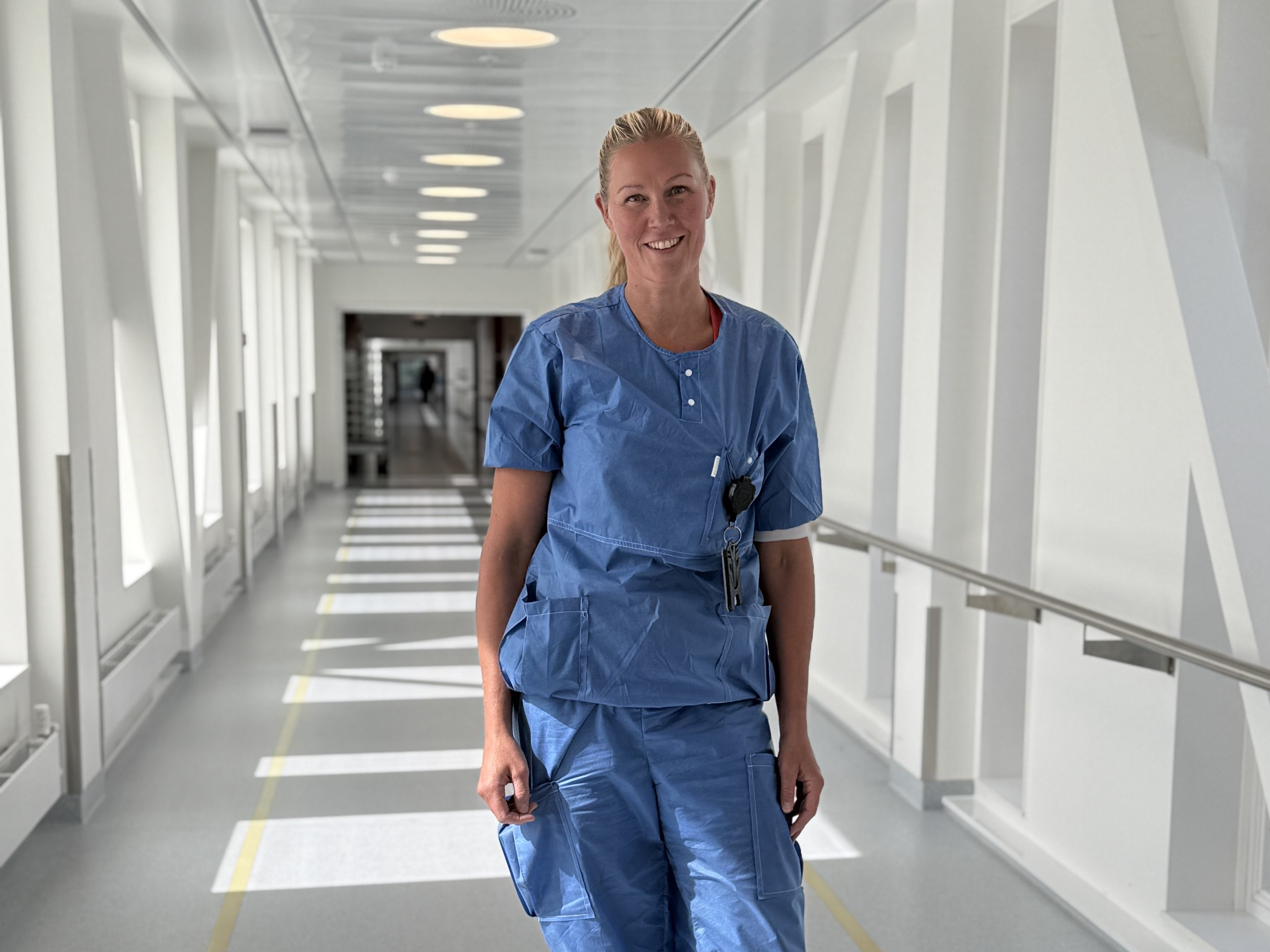 Marianne Holme i blått arbeidstøy og står i en gang på Kalnes