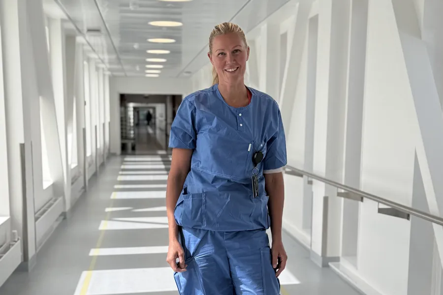 Marianne Holme i blått arbeidstøy og står i en gang på Kalnes