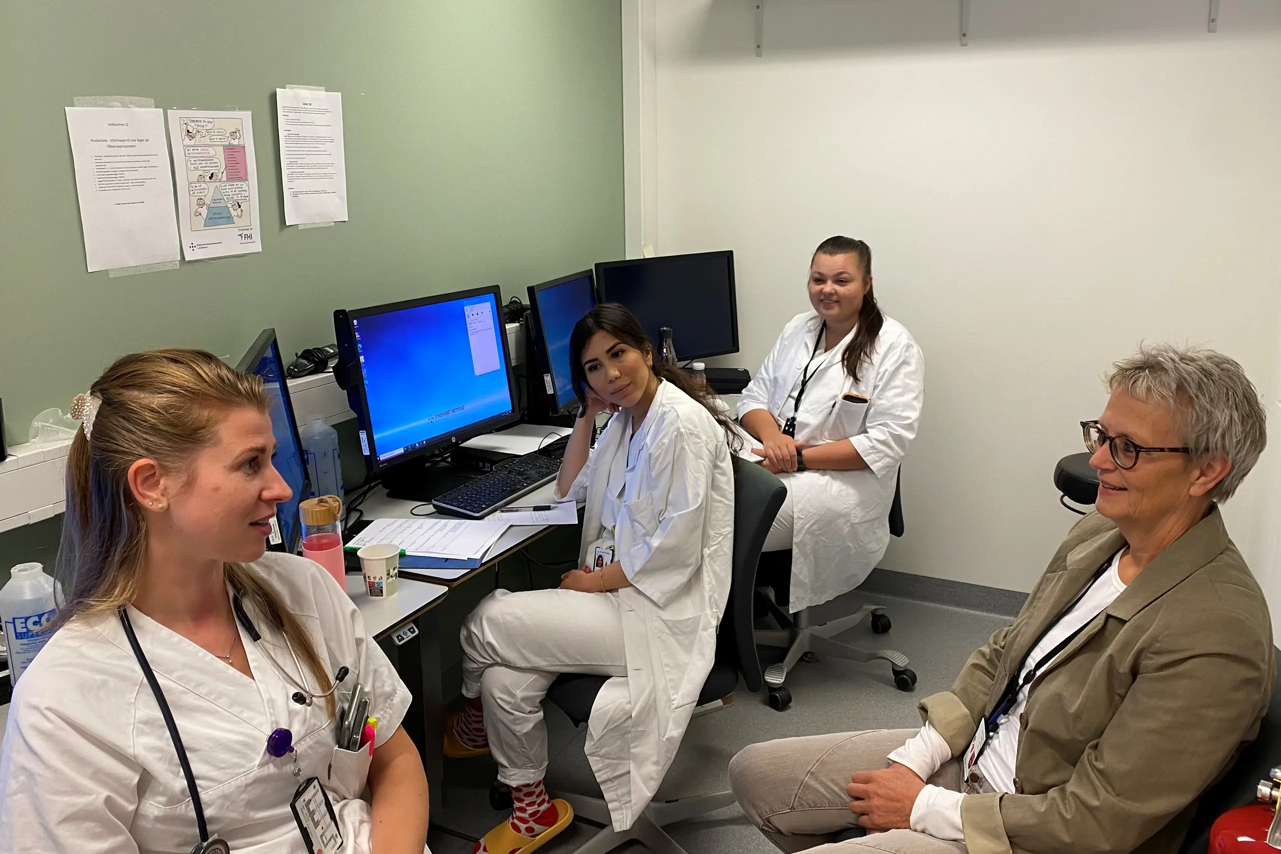 En gruppe mennesker som sitter i et rom med datamaskiner