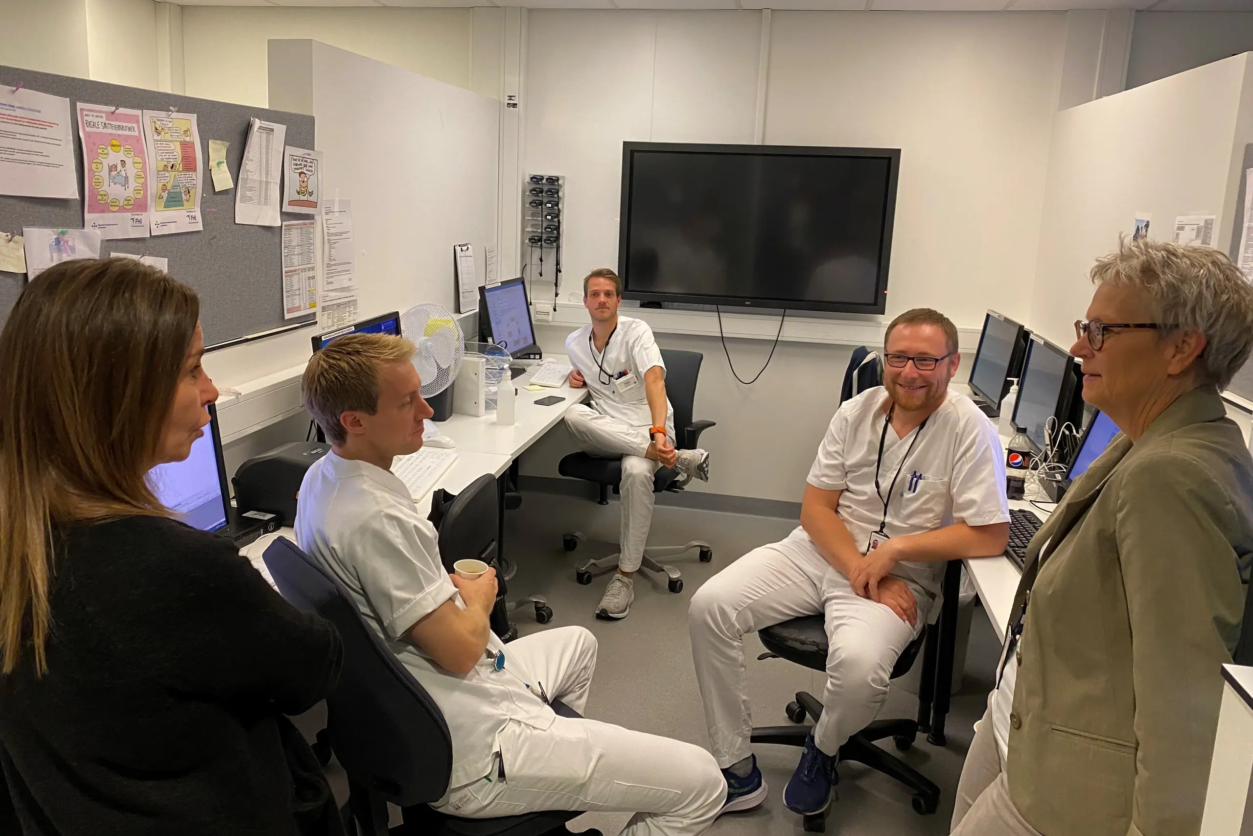 En gruppe mennesker som sitter i et rom med datamaskiner