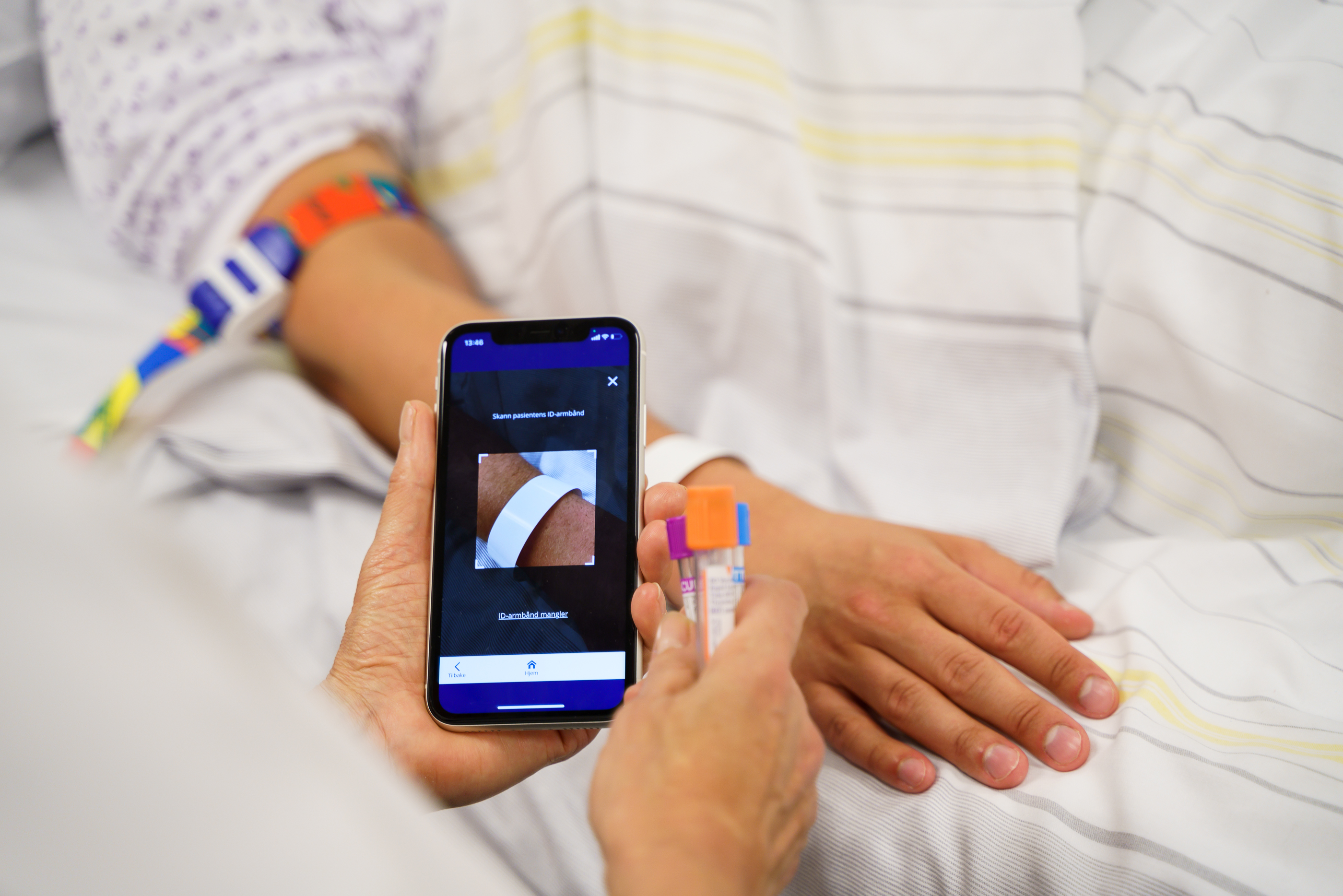 Bilde av et pasientbånd og en mobiltelefon som skanner båndet.