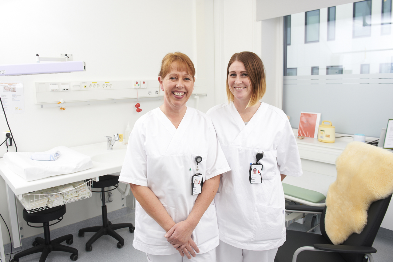 To medarbeidere i hvitt som smiler til kamera