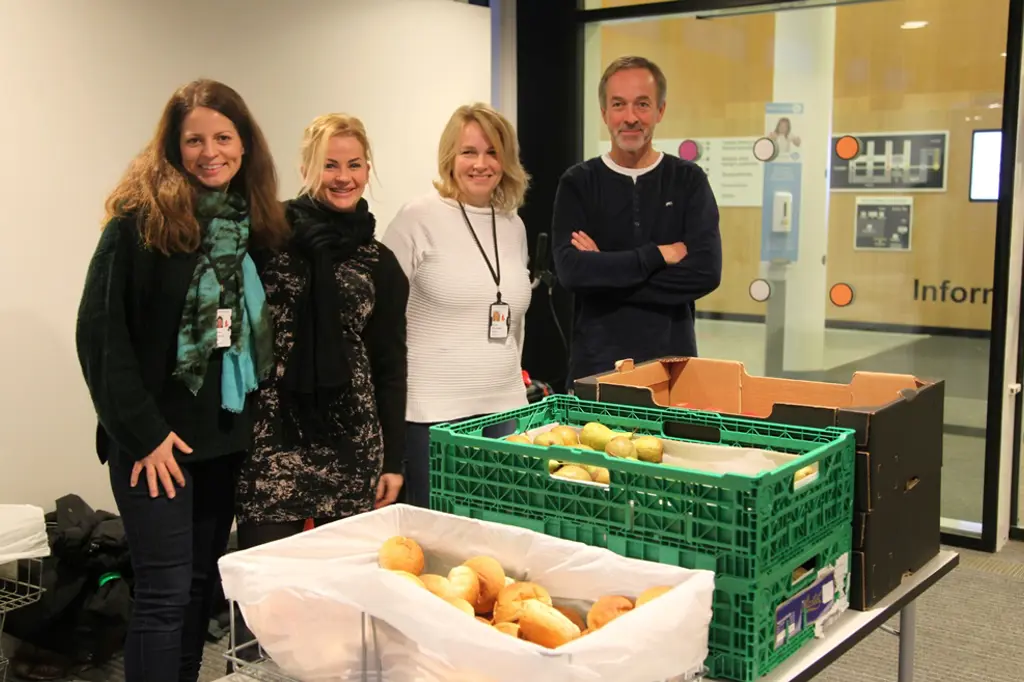 En gruppe mennesker som står ved siden av et bord med smultringer