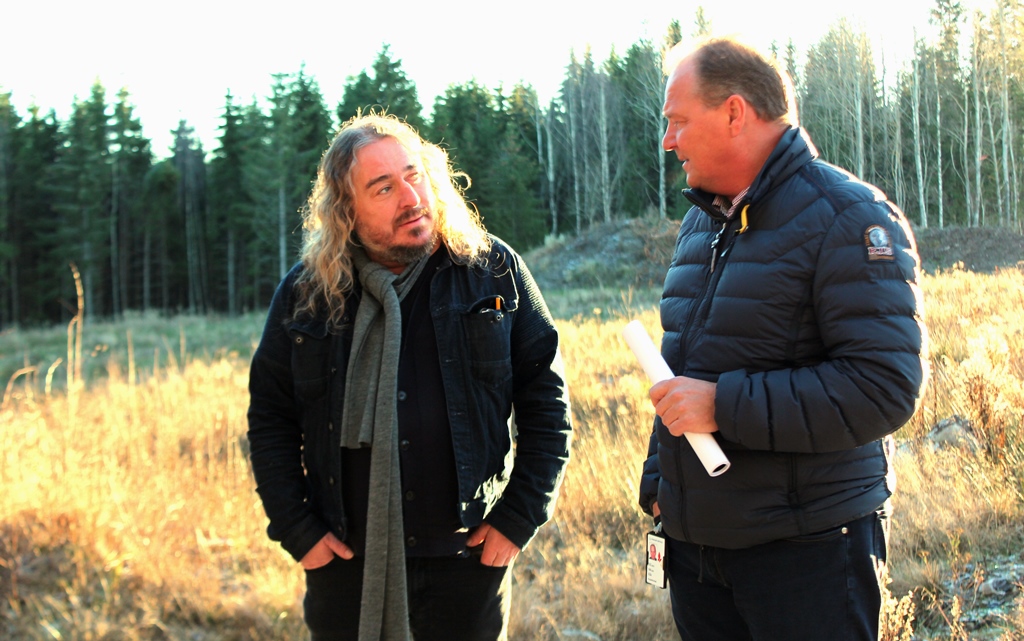 En mann og kvinne som står på et jorde med trær i bakgrunnen