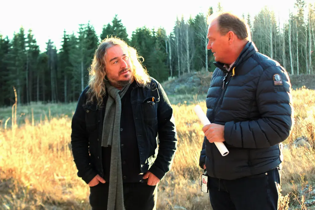 En mann og kvinne som står på et jorde med trær i bakgrunnen