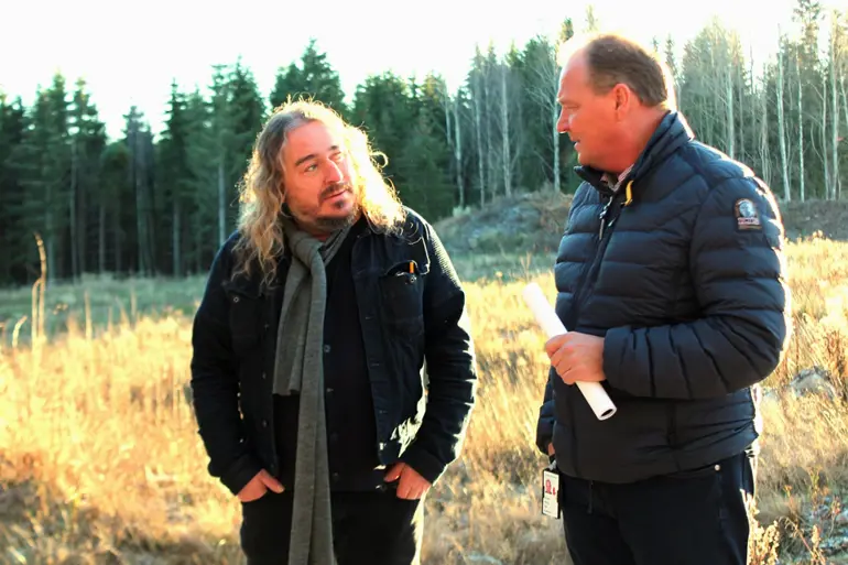 En mann og kvinne som står på et jorde med trær i bakgrunnen