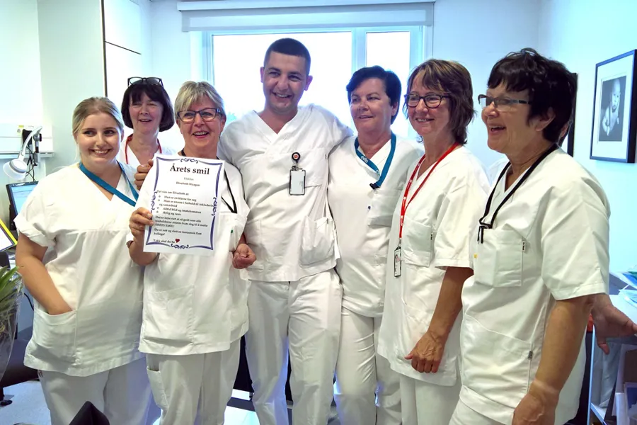 En gruppe mennesker iført hvite labfrakker og holder et skilt