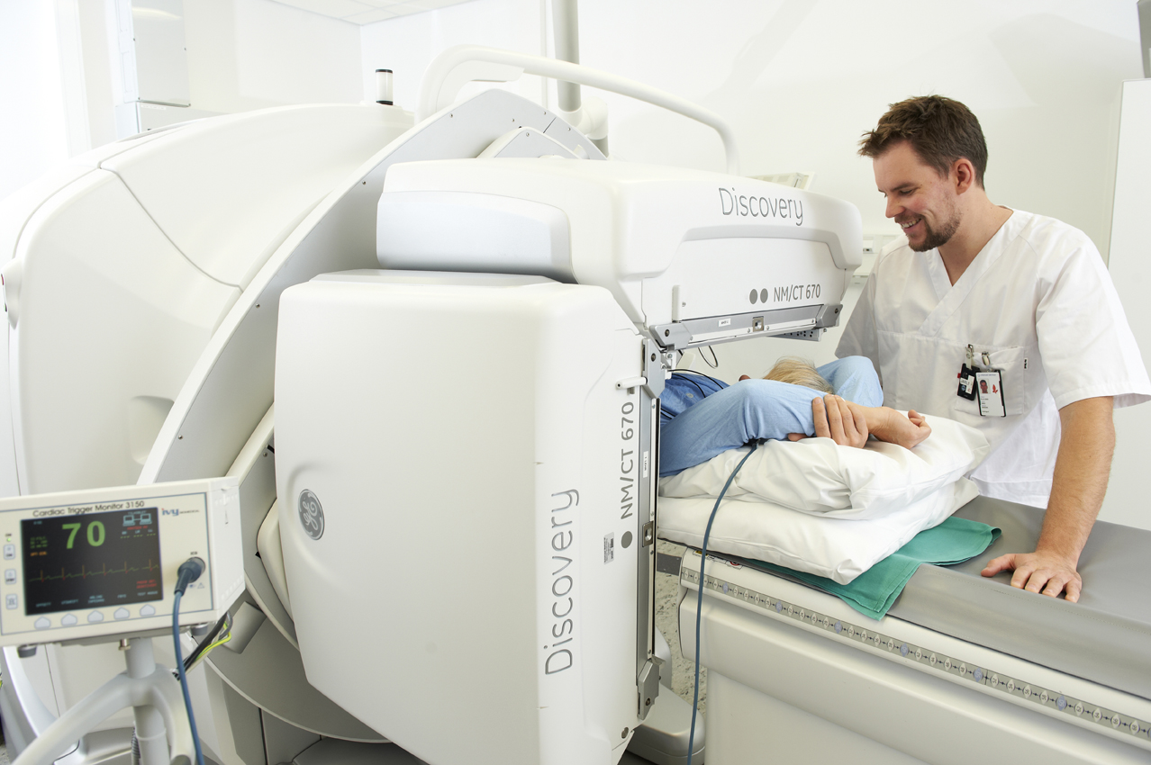 Pasient ligger i en CT-maskin og en radiolog passer på