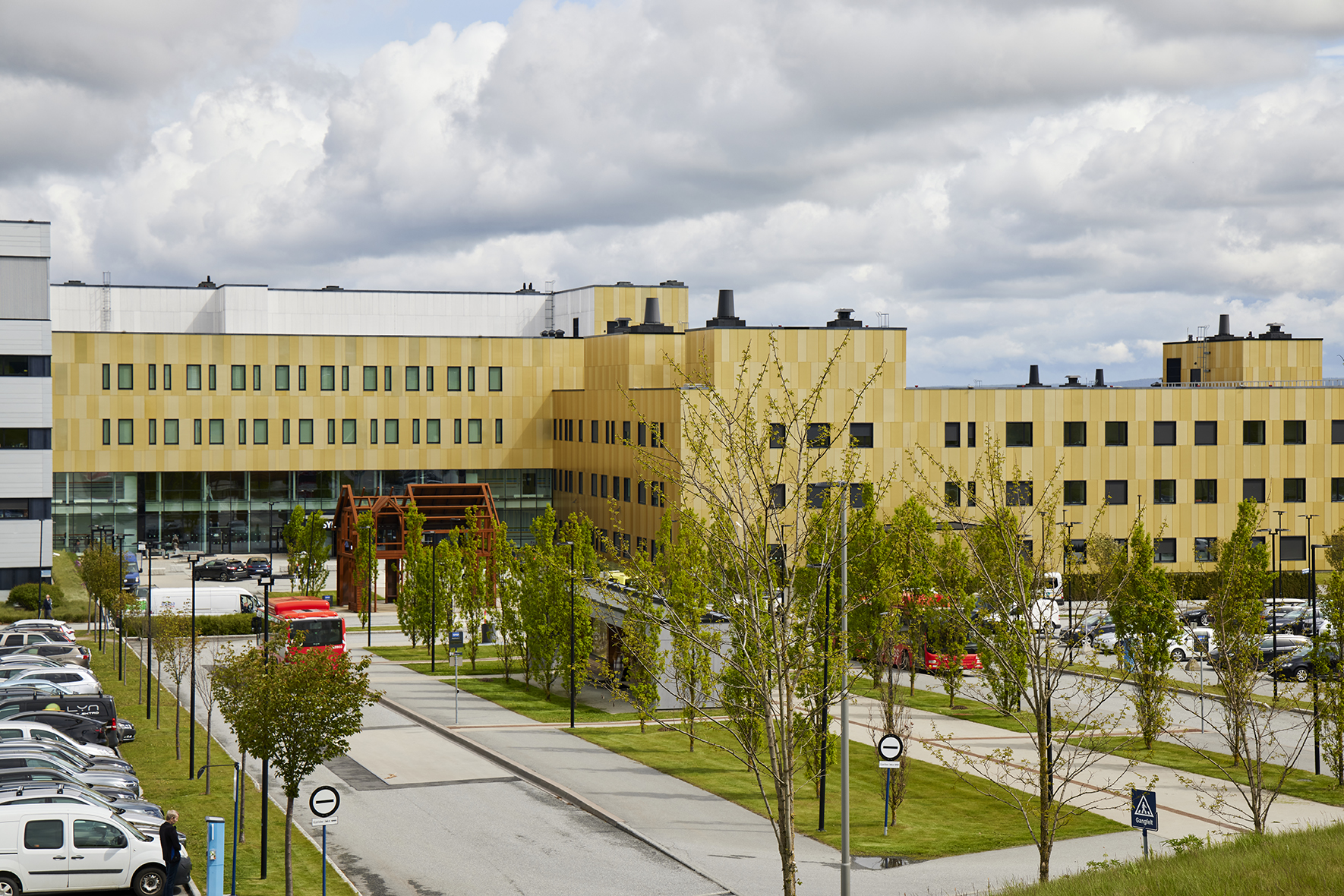 En bygning med trær og biler foran seg