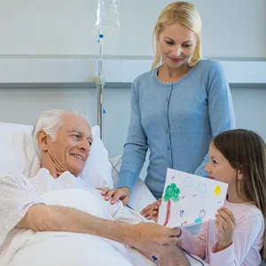 En kvinne og en jente står ved sykehussengen til en eldre mann