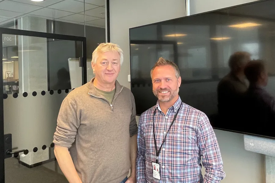 Et par menn poserer for kameraet