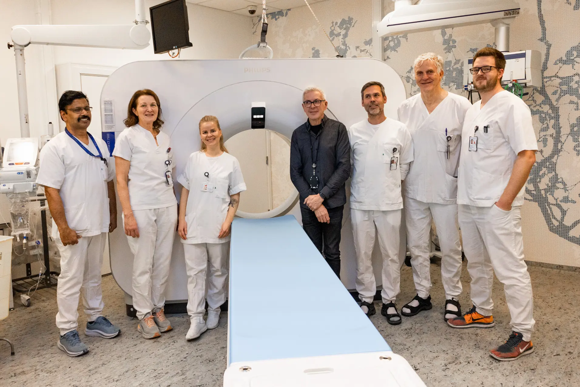 En gruppe mennesker i hvite labfrakker står foran en hvit maskin